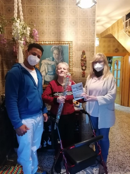 Un auxiliar de ayuda a domicilio de Otura hace entrega de uno de los libros a una vecina (AYTO. OTURA)