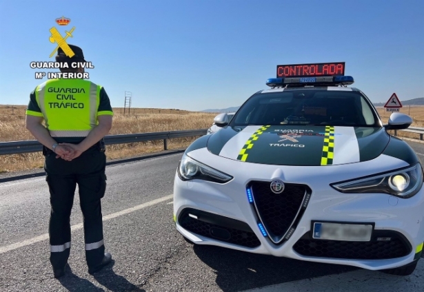 Un agente de la Guardia Civil de Tráfico junto a su vehículo en una carretera (GUARDIA CIVIL)