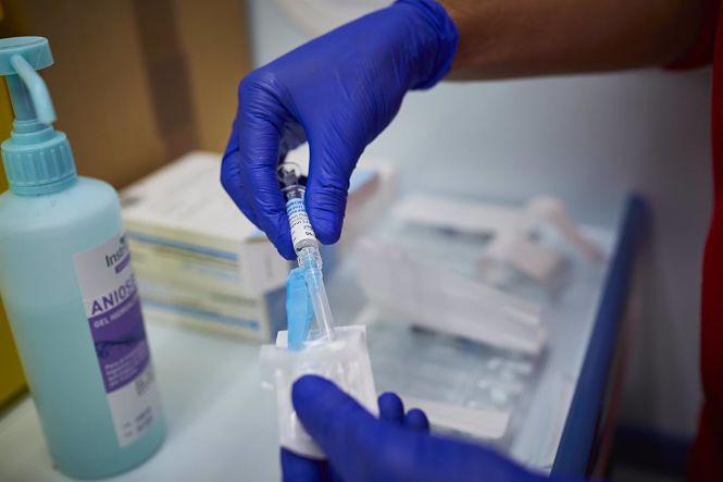 Un sanitario de Cruz Roja se prepara para administrar la vacuna contra la gripe en un punto de vacunación (JESÚS HELLÍN - EUROPA PRESS)