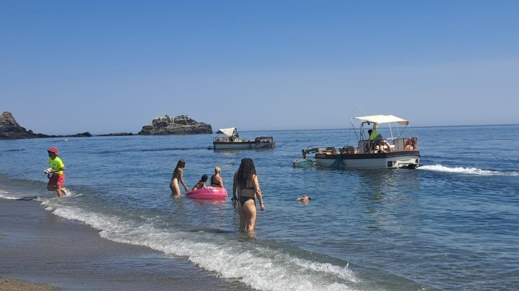 Un barco limpia una playa de Almuñécar (AYTO. ALMIñÉCAR)