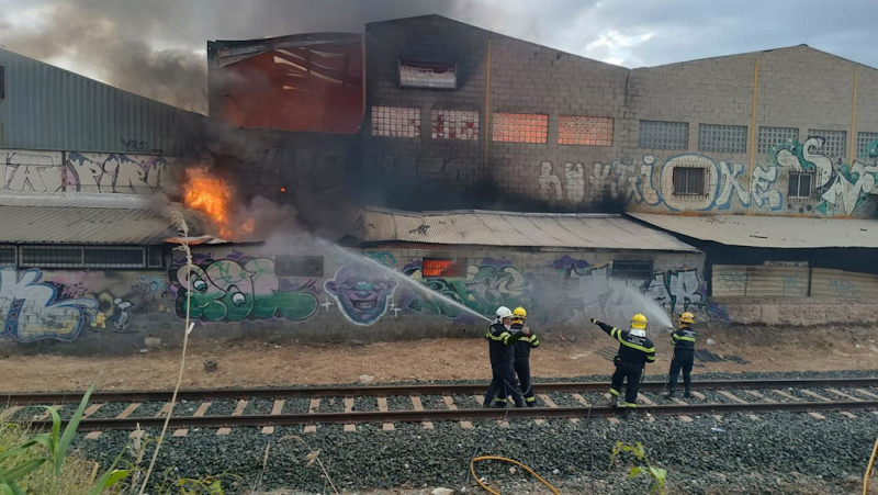 Imagen cedida por Protección Civil de Peligros (Granada) en la que se puede ver a los bomberos trabajando en las tareas de extinción del incendio declarado en una nave industrial de la localidad (PROTECCIÓN CIVIL)PELIGROS