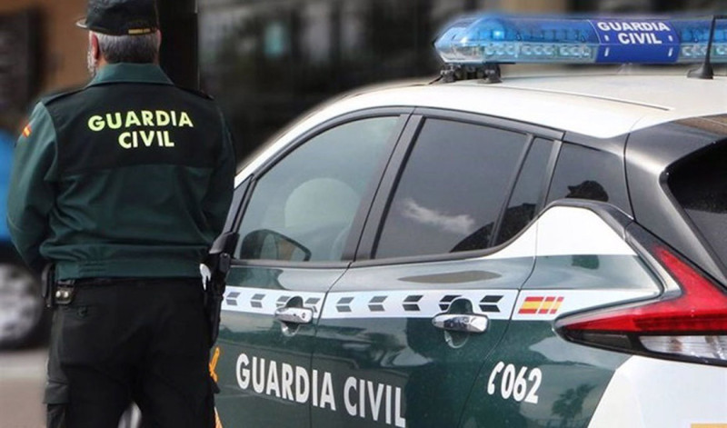 Un agente de la Guardia Civil, de espaldas, de pie junto a un vehículo oficial (GUARDIA CIVIL)